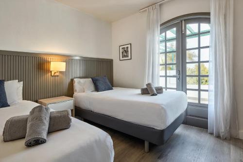 a hotel room with two beds and a window at HG Lomo Blanco in Puerto del Carmen