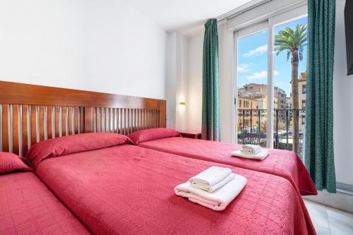 a bedroom with two beds with red sheets and towels at Pensión Veracruz 1 in Granada