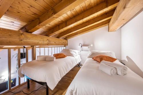 two beds in a room with wooden ceilings at Residence La Piopa in Polpenazze del Garda