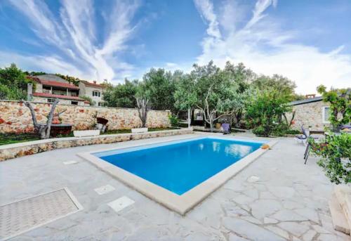 a swimming pool in a backyard with a stone wall at Robinson House with Pool & Seaview in Ždrelac