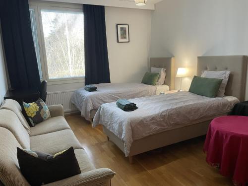 a room with two beds and a couch and a chair at Helsinki Green Retreat in Helsinki