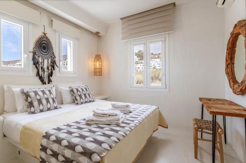 a white bedroom with a bed and two windows at Aeolos Villa Cleo in Agkidia