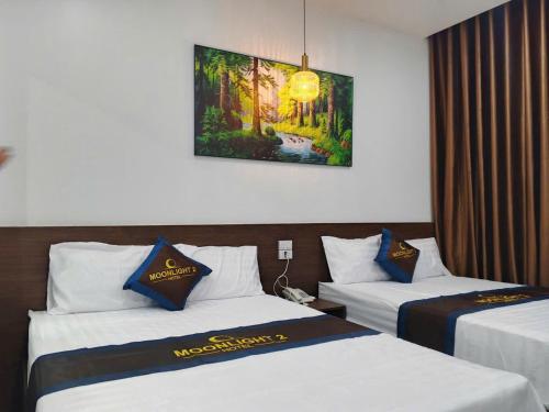 a hotel room with two beds and a painting on the wall at Moonknight 2Hotel in Sầm Sơn