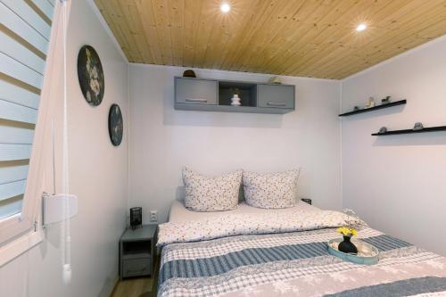 a small bedroom with a bed and a wooden ceiling at Madera Concordiasee in Friedrichsaue