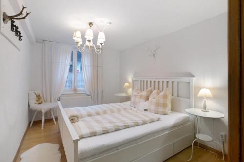 a white bedroom with a bed and a chandelier at Landhaus Dachsberg in Wittenschwand