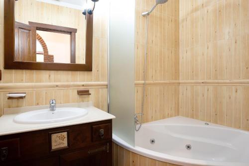 a bathroom with a sink and a tub and a mirror at Villa Canijo in Barbate