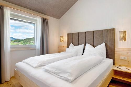 a bedroom with a large white bed with a window at Höllerhof in Cornedo all'Isarco