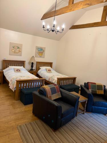 a bedroom with two beds and a couch and chairs at Ystrad Fach Farm in Llangendeirne
