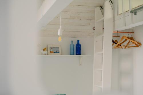 a bathroom with white walls and a white shelf at La Cabane des Goélands Rieurs in Dinard
