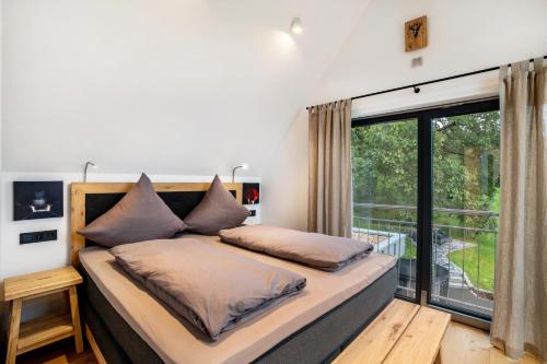 a bedroom with a bed and a large window at Waldlux Luxus-Chalet Brennhus in Kappelrodeck