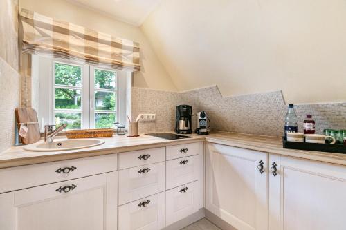 a kitchen with white cabinets and a sink and a window at My Little Rose Cottage in Dörpling