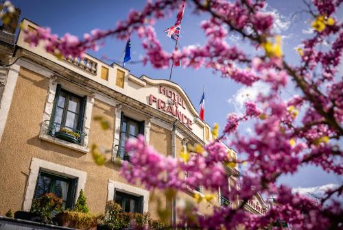 a building with pink flowers in front of it at Logis Hotel De France in La Chartre-sur-le-Loir