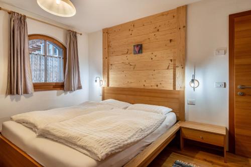 a bed in a bedroom with a wooden wall at Dolomitc Tobià in Campitello di Fassa