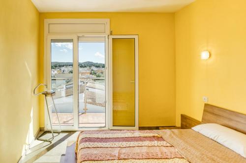 a yellow room with a bed and a balcony at Escala Riells in L'Escala