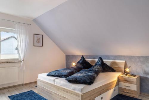 a bedroom with a bed with black pillows on it at Ferienwohnung Schiller in Grebenhain