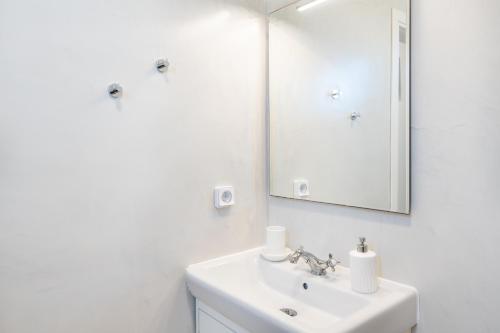 a white bathroom with a sink and a mirror at Irene's Studio in Mikonos
