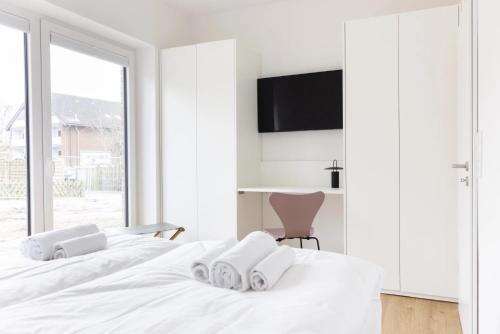 a white bedroom with two white beds and a chair at Koje in Böhl