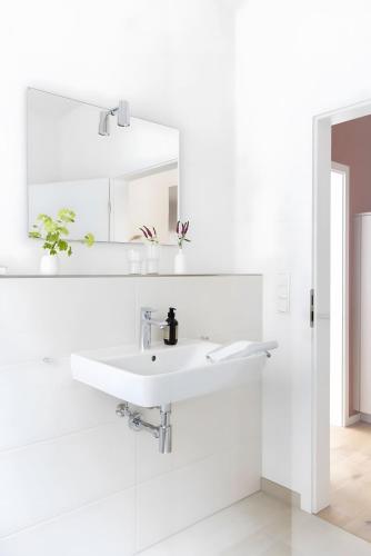 a white bathroom with a sink and a mirror at Koje in Böhl