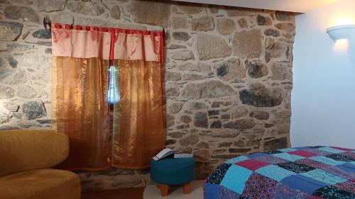 a bedroom with a stone wall with a bed and a window at La Clé des Sens in Castelnau-Pégayrols