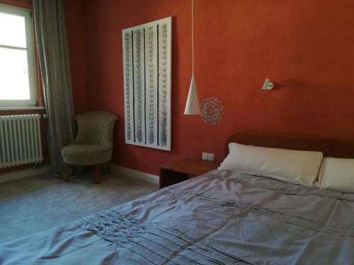 a bedroom with orange walls and a bed and a chair at Ludwig im Künstlerhaus in Langmühle