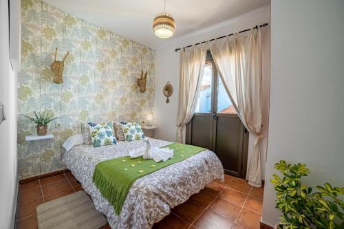 a bedroom with a bed with a green blanket and a window at La Casa Del Bosque in Júzcar