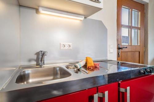 a kitchen with a sink and red cabinets at Obst- Ferienhof Ragg in Immenstaad am Bodensee