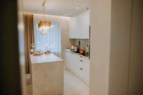 a kitchen with white cabinets and a chandelier at Apartament Kościuszki Nowa Sól in Nowa Sól