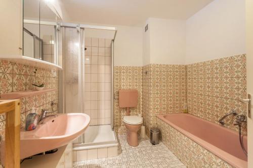 a bathroom with a pink tub and a toilet and a sink at Ferienwohnung Figelius in Herscheid