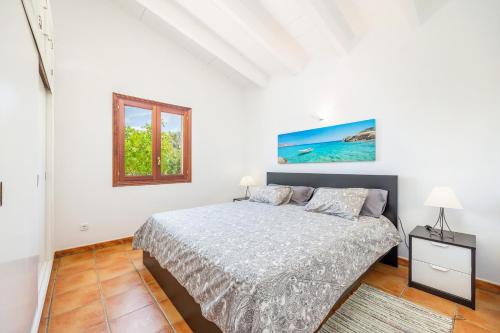 a white bedroom with a bed and a window at Casita Rafal Roig in Maria de la Salut
