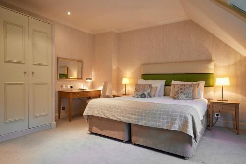 a bedroom with a large bed with two tables and two lamps at Donnington Hotel, Spa & Golf in Newbury