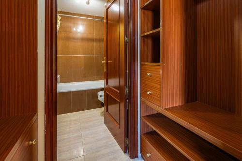 a bathroom with a walk in closet with wooden cabinets at Llac D'alcudia in Port d'Alcudia