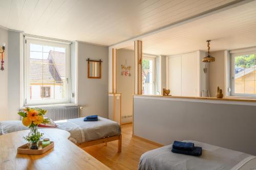 a room with two beds and a table and two windows at Gîte Les 3 Cerfs - 3 étoiles in Plainfaing