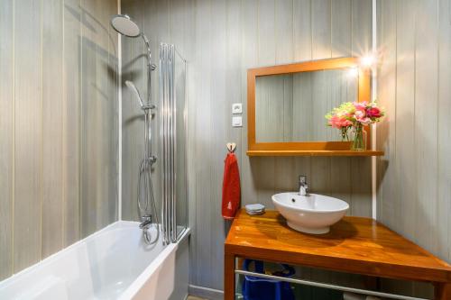 a bathroom with a sink and a mirror and a tub at Gîte Les 3 Cerfs - 3 étoiles in Plainfaing