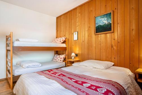 two bunk beds in a room with wooden walls at Appartamento Moti in Caldes