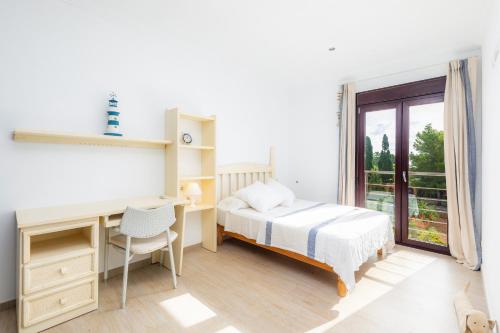 a bedroom with a bed and a desk and a window at Villa Casa Bon Sol in Capdepera