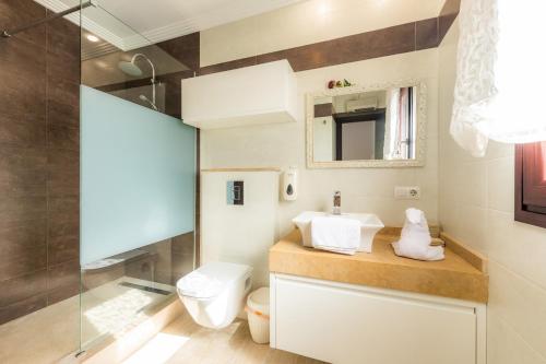 a bathroom with a toilet and a glass shower at Villa Casa Bon Sol in Capdepera