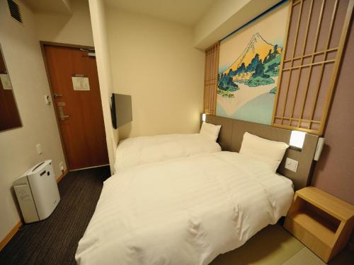 two beds in a hotel room with white sheets at Dormy Inn Akihabara in Tokyo