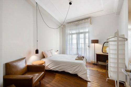 a bedroom with a bed and a chair and a mirror at A Casa Formosa in Porto