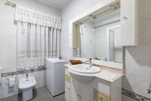 a white bathroom with a sink and a toilet at Piso Calle Sarria in Monforte de Lemos