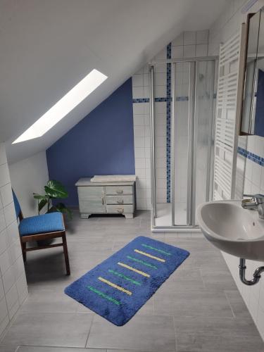 a bathroom with a sink and a shower and a blue rug at Ferienwohnung Pieck in Raduhn