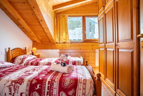 two beds in a room with wooden ceilings at Cuore delle Dolomiti in Tonadico