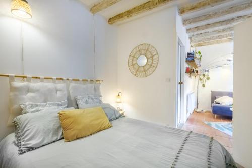 a white bedroom with a large bed with a yellow pillow at Le Jardin des Oiseaux in Clans