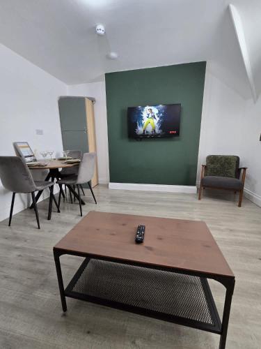 a living room with a table and a tv on a wall at 1 Bed Room Flat with sofa Bed, full kitchen in Weston-super-Mare