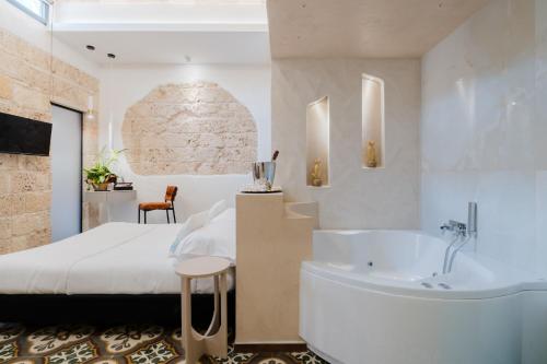 a bedroom with a tub and a bed and a sink at Le Sanpietrane in Taviano