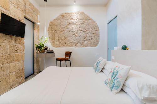 a bedroom with a white bed and a brick wall at Le Sanpietrane in Taviano