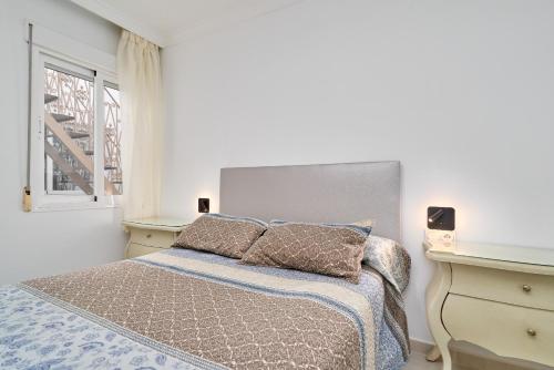 a white bedroom with a bed and a window at Apartamento Lola 2 in Nerja