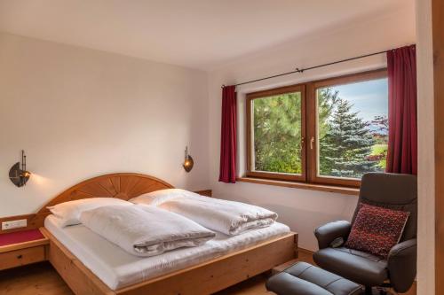 a bedroom with a bed and a chair and a window at Panorama Lodge Leutasch mit Sauna in Leutasch