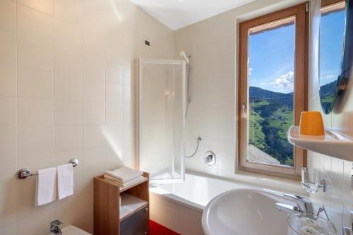 a white bathroom with a sink and a window at Al Cargá San Vigilio di Marebbe in San Vigilio Di Marebbe