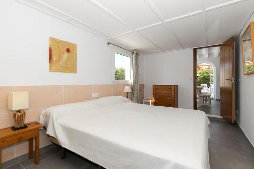 a white bedroom with a large bed and a window at Ca Sa Mola in Cala Santandria