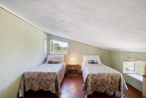 two beds in a small room with a window at Emma e Adele House in Marlia